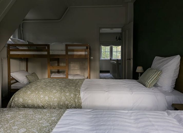 Stijlvolle woonkamer in Huisje in Lunteren, Veluwe, met comfortabele leren bank en uitzicht op de tuin.