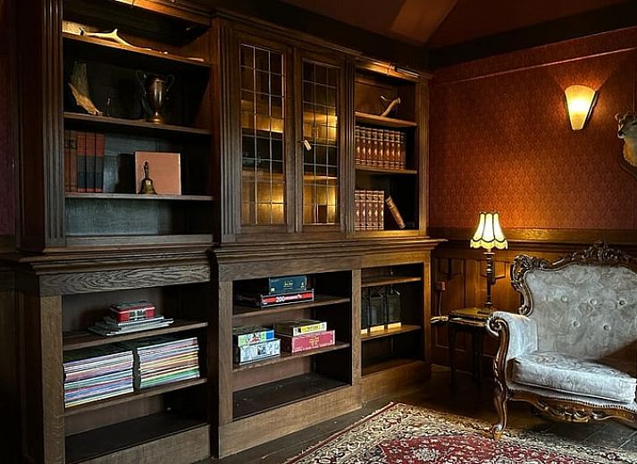 Stijlvolle woonkamer in Huisje in Lunteren, Veluwe, met comfortabele leren bank en uitzicht op de tuin.