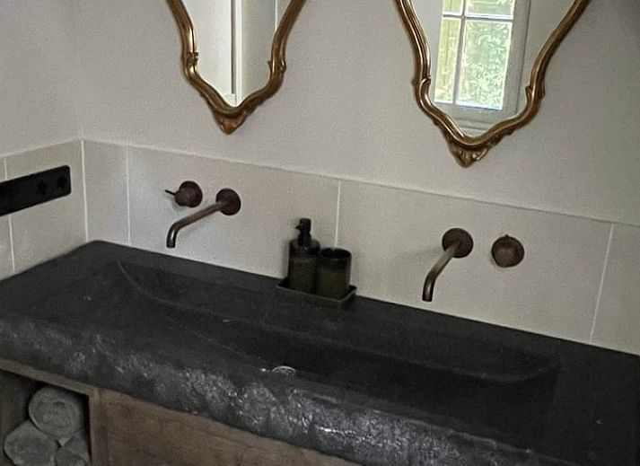 Stijlvolle woonkamer in Huisje in Lunteren, Veluwe, met comfortabele leren bank en uitzicht op de tuin.