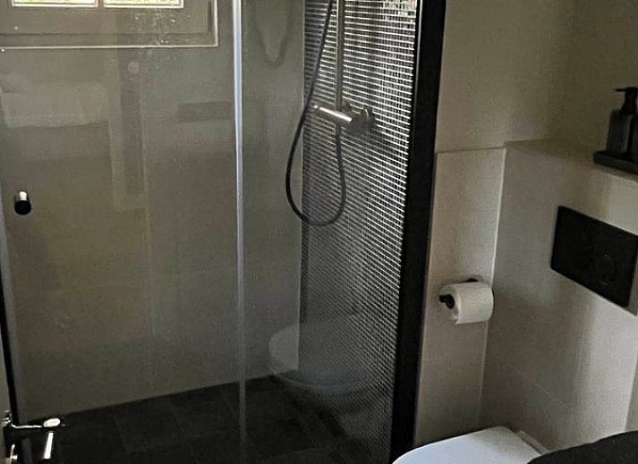 Stijlvolle woonkamer in Huisje in Lunteren, Veluwe, met comfortabele leren bank en uitzicht op de tuin.