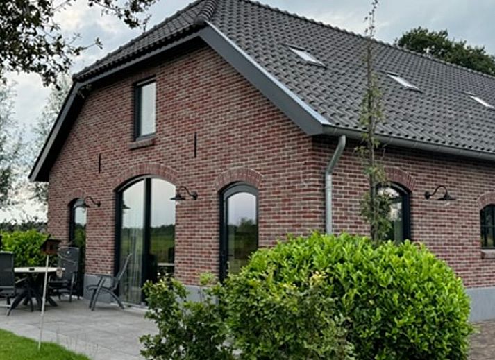 Ferienhaus in Lunteren in der Veluwe, Gelderland, umgeben von einer bunten Blumenwiese und gruener Natur.