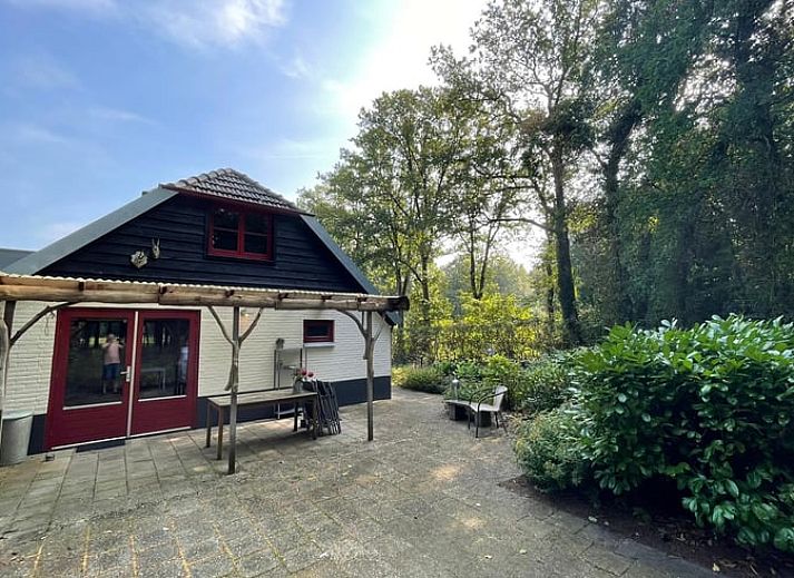 Charmantes Ferienhaus in Wapenveld, Veluwe, Gelderland mit rustikaler Fassade und laendlicher Umgebung.