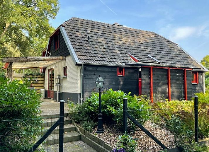 Charmantes Ferienhaus in Wapenveld, Veluwe, Gelderland mit rustikaler Fassade und laendlicher Umgebung.