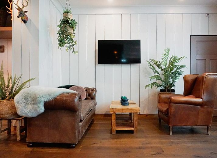 Gezellige eetruimte in Forest Hotel Den Helder, vakantie appartement met houten wanden en botanische prints.