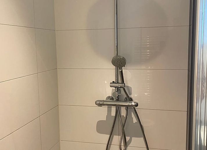 Tuin van vakantiehuisje in Bennekom met ligstoelen en kleurrijke bloemen, midden in de Veluwe.