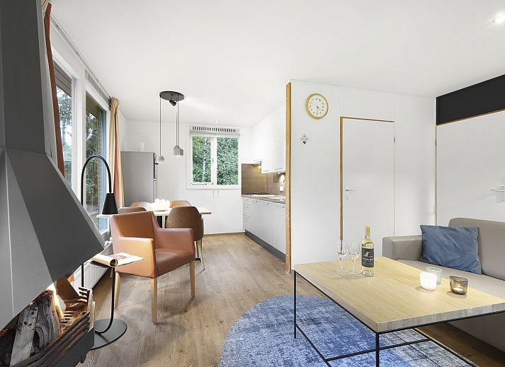 Sfeervolle woonkamer met open haard en grote ramen in Coldenhove bungalow, Eerbeek, Veluwe.