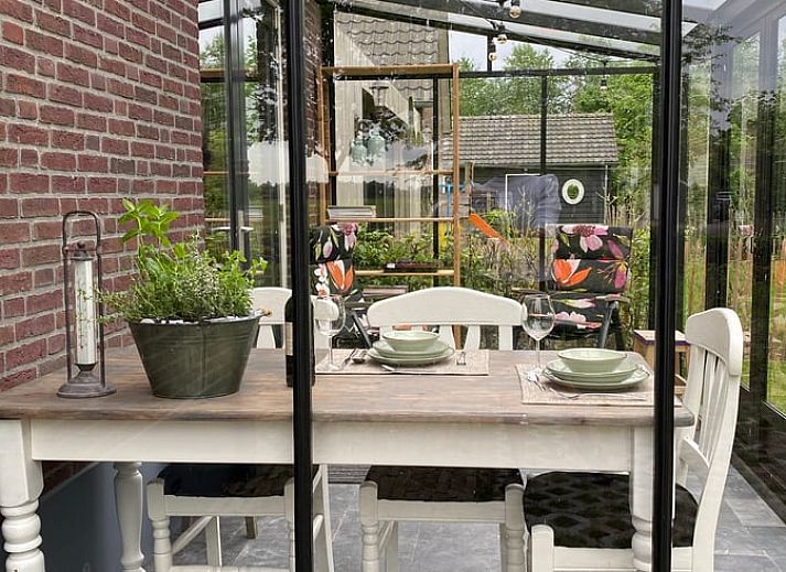 Buitenterras van Vakantiehuisje in Kootwijkerbroek, Veluwe, met zitje en parasol in een groene omgeving.