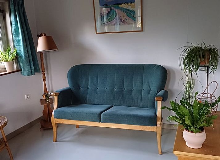 Charmante veranda bij Vakantiehuisje in Uithuizermeeden, Noordoost Groningen, omringd door bloemen en groen.