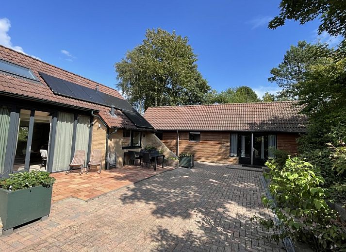 Robbenoort 127, 'Lauwie' vakantiehuis in Lauwersoog, Groningen, omgeven door groene natuur en rustieke architectuur.