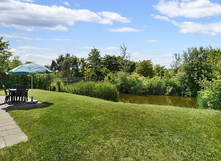 Gemuetlicher Kamin mit Wein und Zeitschriften im Natuurdorp Suyderoogh Bungalow in Lauwersoog, Groningen.