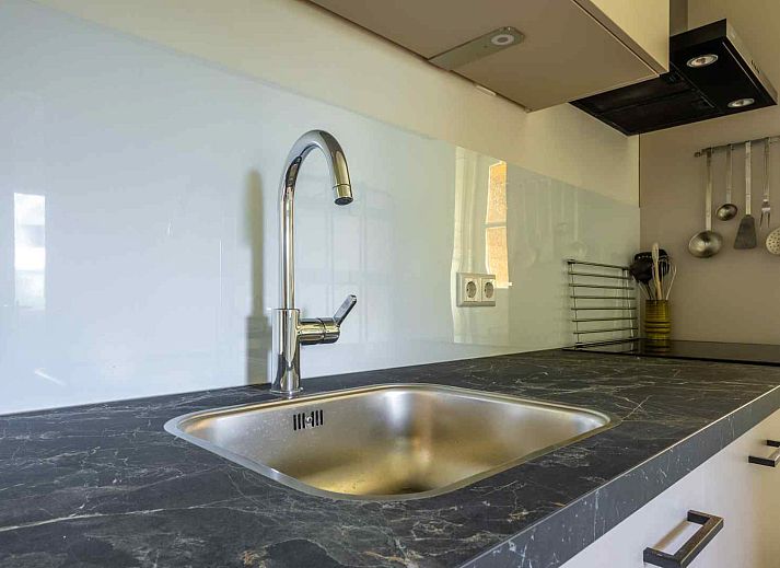 Zonnig terras bij GR032 vakantiehuis in Lauwersoog, omgeven door bloeiende planten.