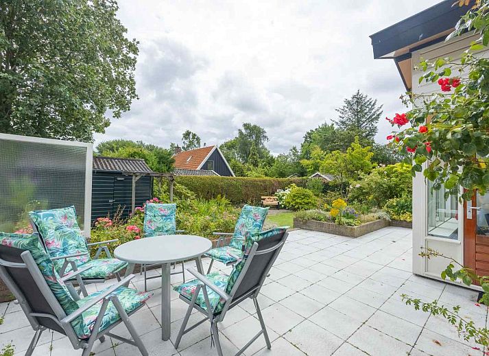 Zonnig terras bij GR032 vakantiehuis in Lauwersoog, omgeven door bloeiende planten.