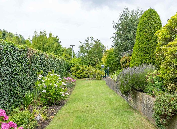 Zonnig terras bij GR032 vakantiehuis in Lauwersoog, omgeven door bloeiende planten.
