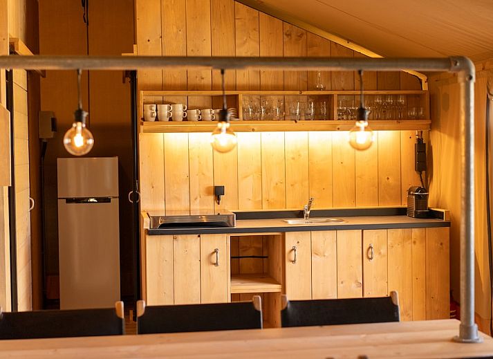 Gezellige veranda van Safaritent 6 in Vierhuizen, Groningen met houten meubels en ruime binnenruimte voor een ontspannen glamping ervaring.