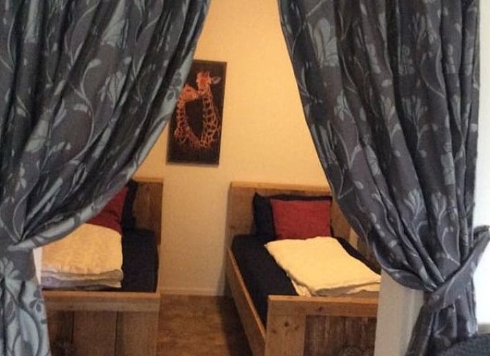 Attraktives Schlafzimmer im Huisje in Ter Apel, einem Ferienhaus im Suedosten von Groningen mit rustikalen Holzbetten und warmen Akzenten.