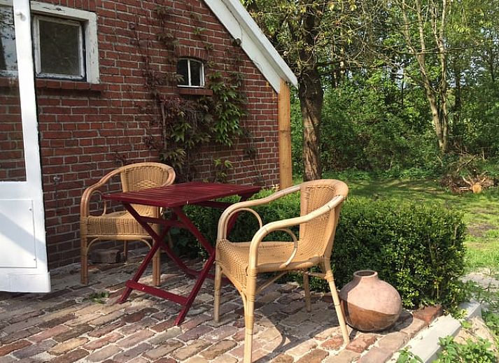 Houten schuur en bloeiende struiken bij Vakantiehuisje in Vriescheloo, Zuidoost Groningen, accentueren de landelijke charme van deze vakantiewoning.