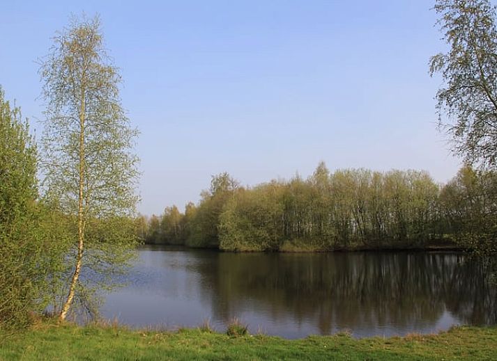 Houten schuur en bloeiende struiken bij Vakantiehuisje in Vriescheloo, Zuidoost Groningen, accentueren de landelijke charme van deze vakantiewoning.