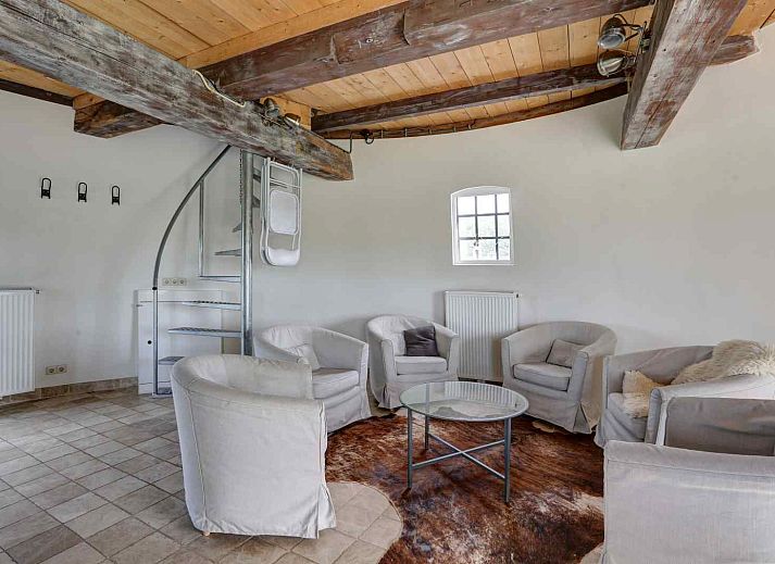 Gezellige woonkamer van GR029 in Tripscompagnie, Groningen met een sfeervolle spiraaltrap en houten balkenplafond.