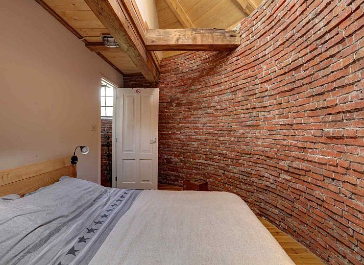 Knusse slaapkamer met houten balken in vakantiehuis GR029, Tripscompagnie, Groningen voor een rustieke overnachting.