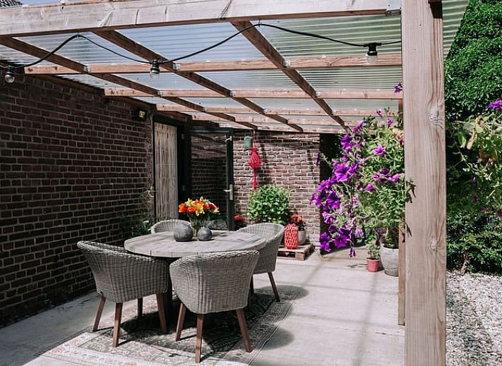 Entree van Vakantiehuis in Well, Noord Limburg met kleurrijke stoelen en bloeiende planten.