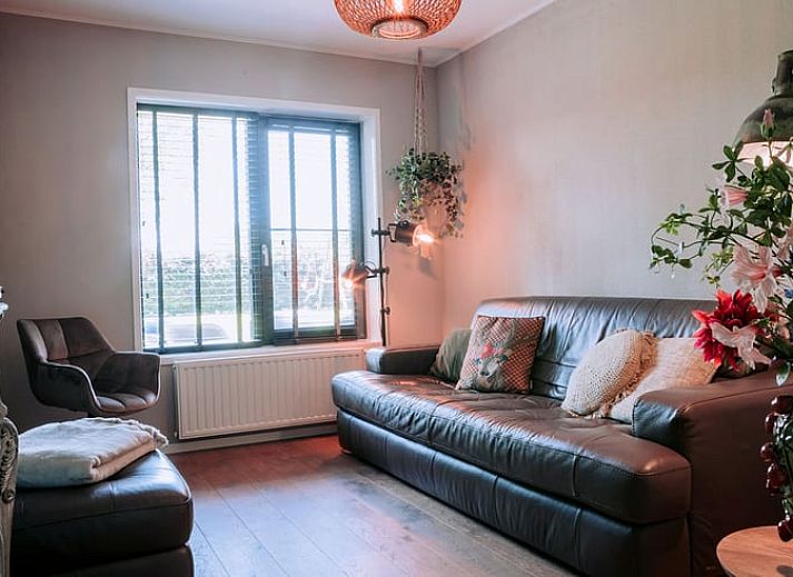 Entree van Vakantiehuis in Well, Noord Limburg met kleurrijke stoelen en bloeiende planten.