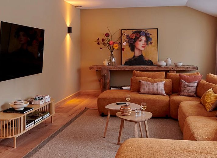 Gemuetliches Wohnzimmer im Ferienhaus in Baarlo, Nord-Limburg. Gemuetliche Sitzecke mit warmer Beleuchtung und modernen Moebeln.