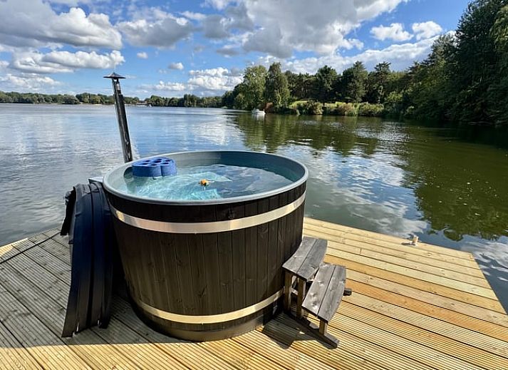 Ontspan in de hot tub op het terras van Vakantiehuisje in Middelaar, Noord Limburg, met uitzicht op het serene water en omringende natuur.