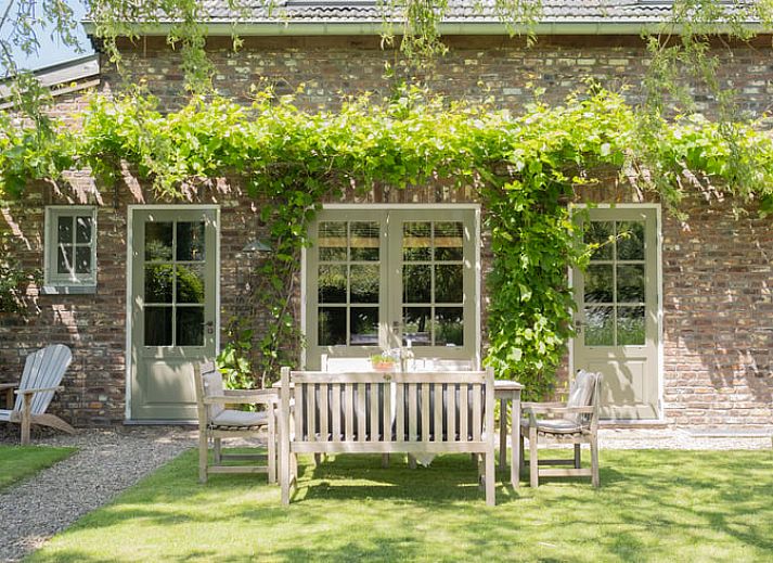 Zonnig terras met houten tafel bij Huisje in Slenaken vakantiehuis in Limburg.