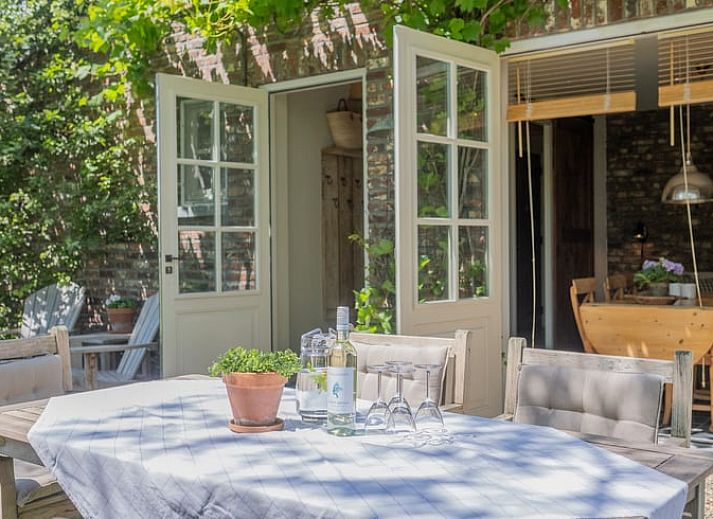 Zonnig terras met houten tafel bij Huisje in Slenaken vakantiehuis in Limburg.