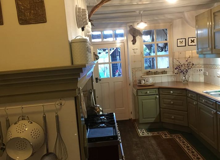Red front door of Holiday home in Epen, South Limburg, surrounded by green bushes.