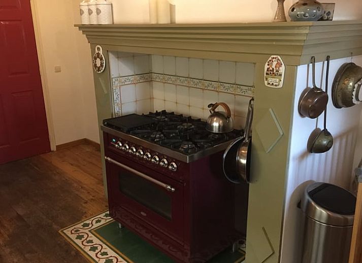 Red front door of Holiday home in Epen, South Limburg, surrounded by green bushes.