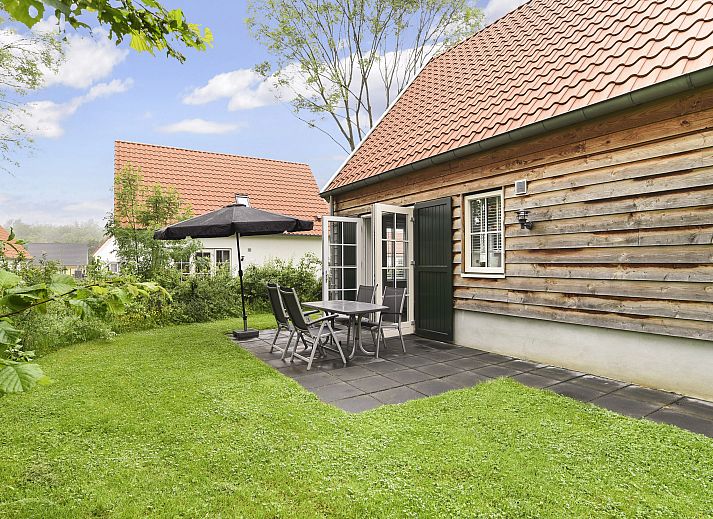 Charming wooden facade of De Waufsberg vacation home in Noorbeek, Limburg, surrounded by greenery.