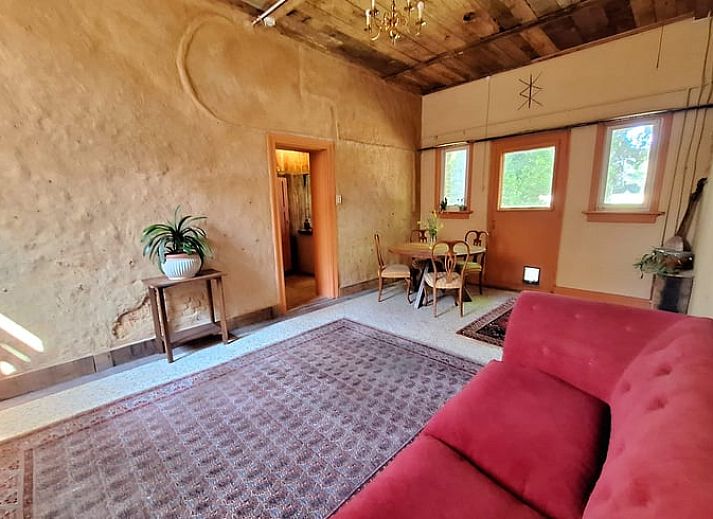 Gezellige woonkamer in Vakantiehuis in Heerlen, Zuid Limburg met comfortabele bank en houten plafond.