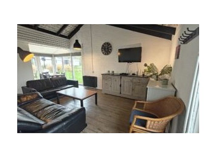 Sonnige Terrasse des Ferienhauses Korenwolf, Simpelveld, Suedlimburg mit Gartentisch und Sonnenschirm in gruener Umgebung.