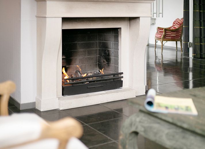 Luxury interior of Kasteeldomein De Cauberg penthouse in Valkenburg, South Limburg, with elegant living room and cozy fireplace.