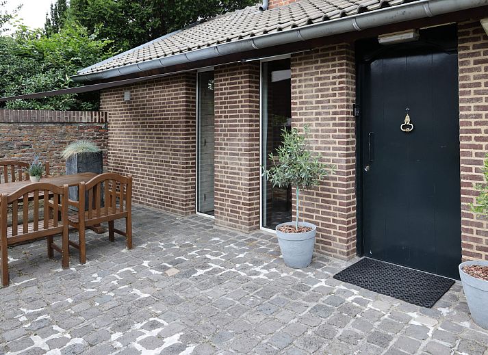 Stijlvolle zitruimte in L173 vakantiehuis, Sittard, Zuid Limburg, met rustieke houten muren en bloemendecoratie.