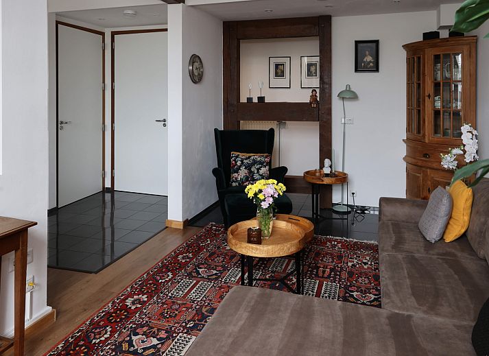 Stijlvolle zitruimte in L173 vakantiehuis, Sittard, Zuid Limburg, met rustieke houten muren en bloemendecoratie.