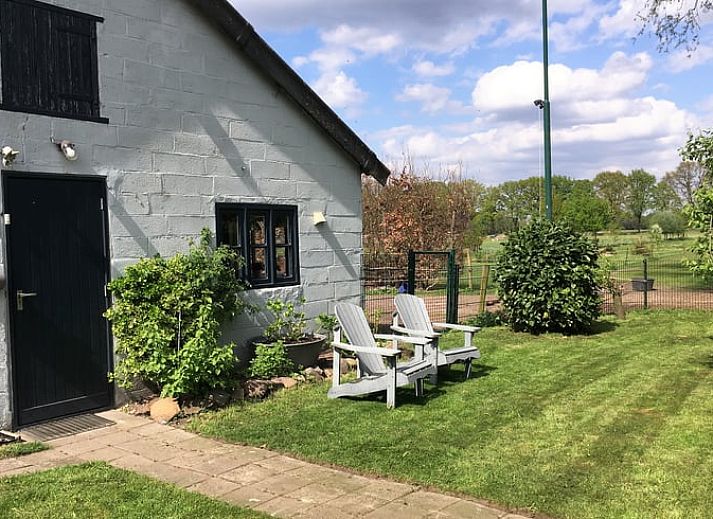 Rustige tuin bij Vakantiehuisje in Aarle-Rixtel, Noord Brabant, met groene omgeving en comfortabele stoelen.
