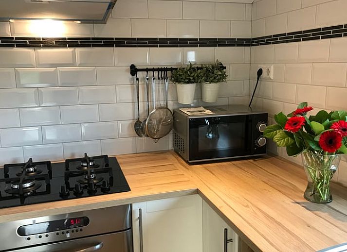 Ontspan op de veranda van Huisje in Baarle-Nassau, vakantiehuis in Noord Brabant, omringd door kleurrijke bloemen.