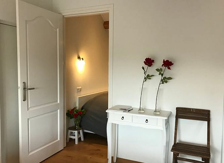 Ontspan op de veranda van Huisje in Baarle-Nassau, vakantiehuis in Noord Brabant, omringd door kleurrijke bloemen.