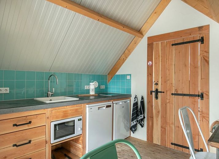 Gemuetliche Essecke im Cottage in Eersel, Ferienhaus in den Kempen, Nordbrabant, mit bunten Stuehlen und Holztisch.