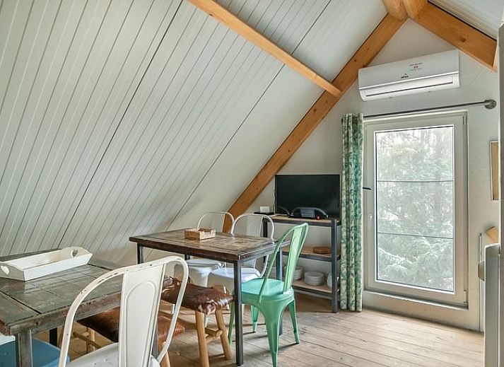 Gemuetliche Essecke im Cottage in Eersel, Ferienhaus in den Kempen, Nordbrabant, mit bunten Stuehlen und Holztisch.