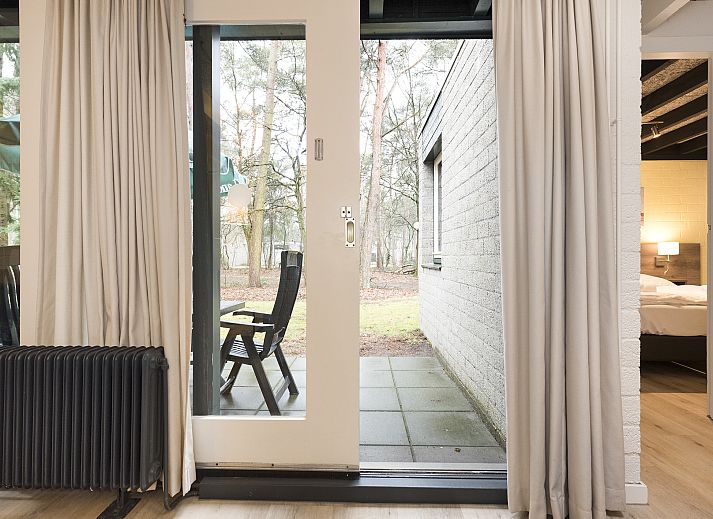 Blick auf die Terrasse vom Wohnzimmer des 5-Personen-Bungalows 5B1 von Het Vennenbos in Hapert, umgeben von Natur.