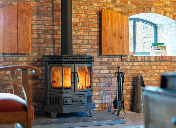 Gezellige woonkamer met houtkachel in De Hoeve I, vakantiehuis in Hulsel, Kempen, Noord Brabant.