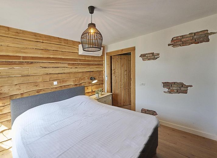 Gezellige zithoek met open haard in De Hoeve III, vakantiehuis in Hulsel, omgeven door rustieke houten wanden in de Kempen.