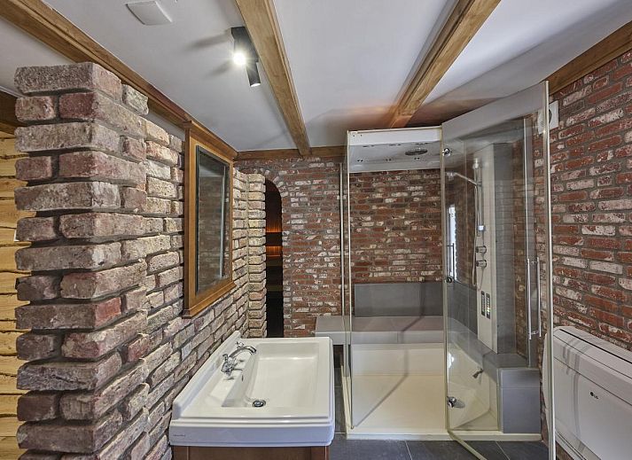 Gezellige zithoek met open haard in De Hoeve III, vakantiehuis in Hulsel, omgeven door rustieke houten wanden in de Kempen.