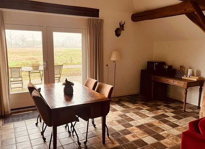 Gezellige binnenruimte van het vakantiehuis in Udenhout met openstaande deuren naar terras.