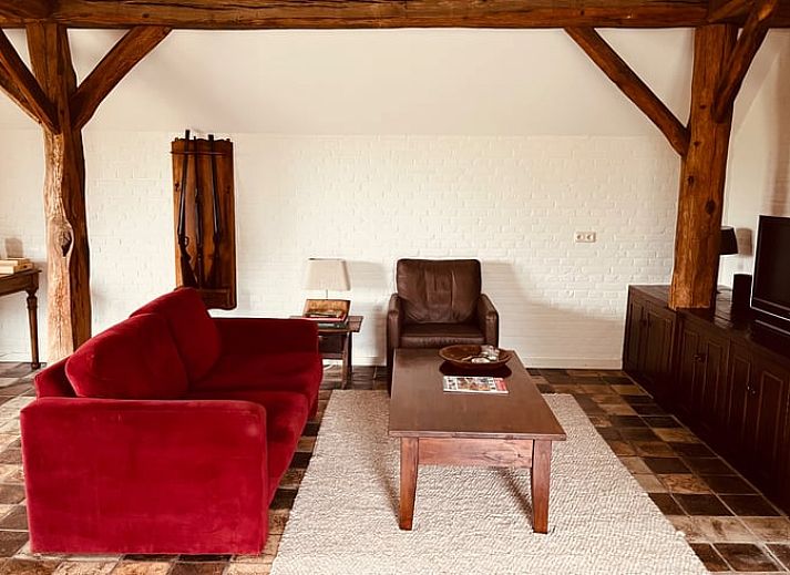 Gezellige binnenruimte van het vakantiehuis in Udenhout met openstaande deuren naar terras.