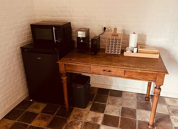 Ruime woonkamer met houten balken en open haard in vakantiehuis Udenhout, Hart van Brabant.