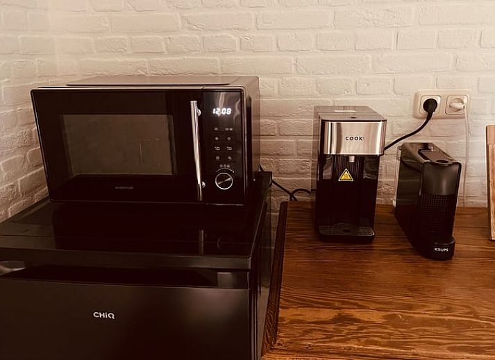 Ruime woonkamer met houten balken en open haard in vakantiehuis Udenhout, Hart van Brabant.